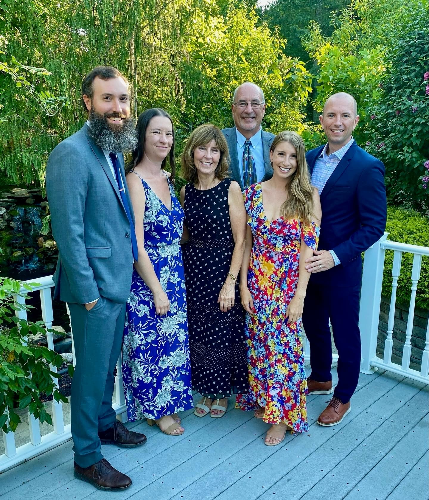 Brett with extended family in wedding-guest attire on a garden deck